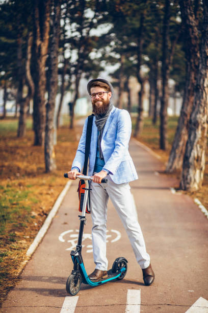 istock Young businessman with a beard smiling on kick scooter 1129573838