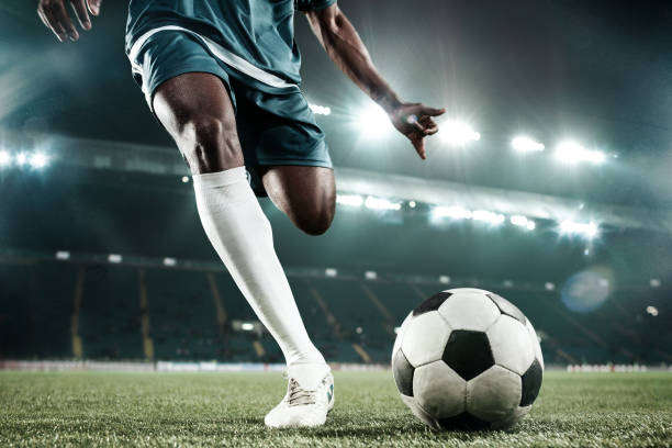 legs of soccer player kicking the ball - chutando imagens e fotografias de stock