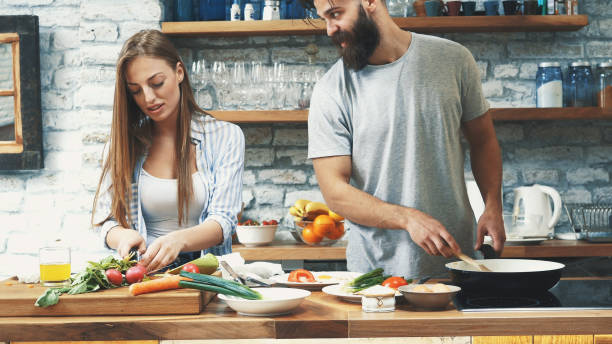 istock Young couple making dinner together at home 1129579273