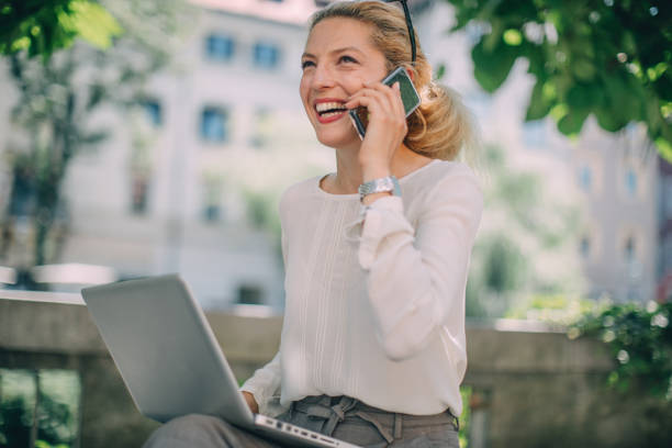 istock Blonde modern woman using laptop outdoors 1129579302