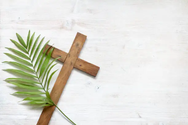 Photo of Cross and palm on wooden white background easter sign symbol concept