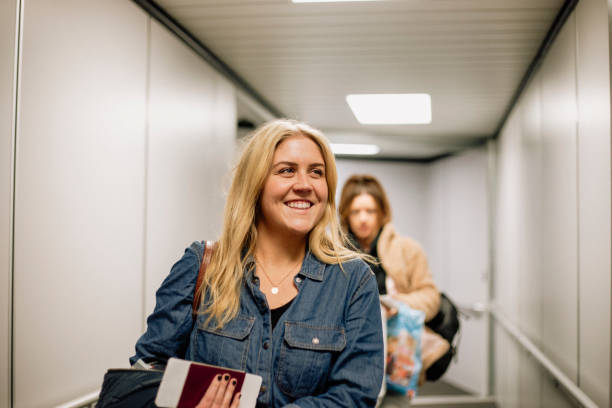 Time to Travel Home A close-up shot of a mid adult woman walking through a passenger boarding bridge, she looks excited with a smile on her face as she boards her flight. passenger boarding bridge stock pictures, royalty-free photos & images