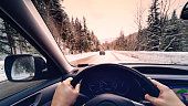 scenic view of a road with snow covered landscape while snowing in winter season -  POV, first person view shot