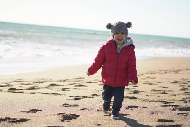 Little Boy running at the beach in winter sunny day.
