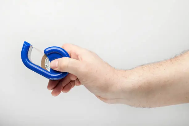 Male hand hold a scotch tape, isolated  on the white background.