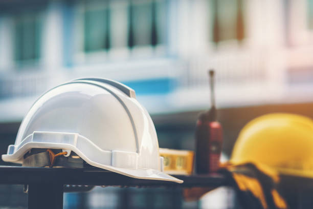 casco bianco e giallo con acqua da costruzione, guanti e radio che sono posizionati sulla recinzione della casa in acciaio. - costruzione worker foto e immagini stock