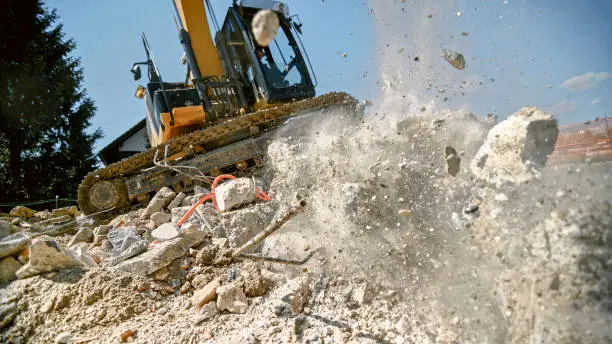 Photo of Excavator grapples crushing concrete block in air