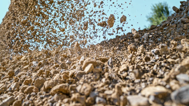 Gravel falling of digger at construction site Gravel being unloaded from bucket of digger at construction site. gravel mound stock pictures, royalty-free photos & images