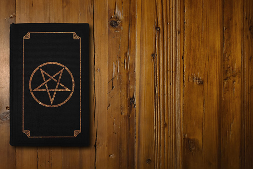 Libro satánico en un tablero de madera marrón photo