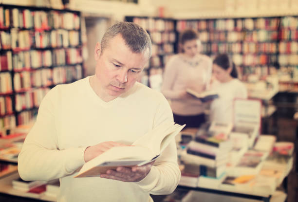 istock Male reading books in bookshop 1129584756