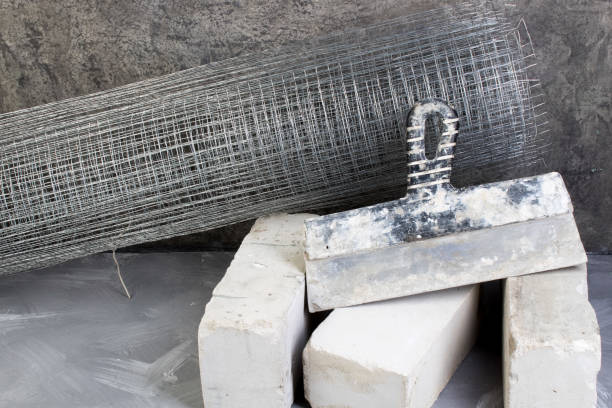 istock roll mesh for plastering, putty knife bricks, hammer on the gray concrete background. Copy space. Top view. gray concrete. 1129585633
