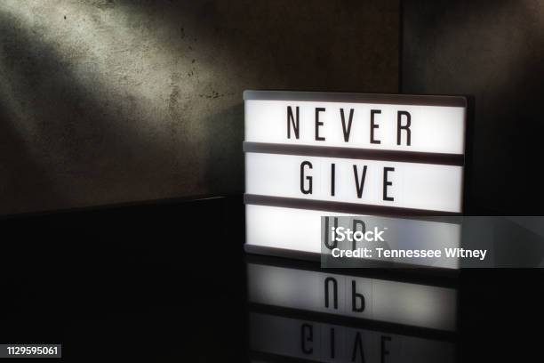 Never Give Up Motivational Message On A Light Box Stock Photo - Download Image Now - Conquering Adversity, Lightbox, Showing