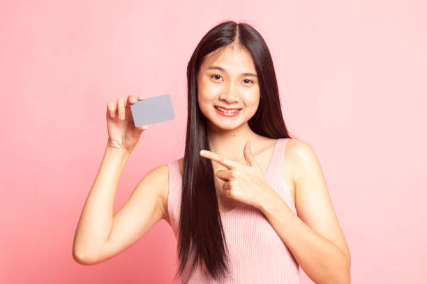 istock Young Asian woman point to a blank card. 1129595167