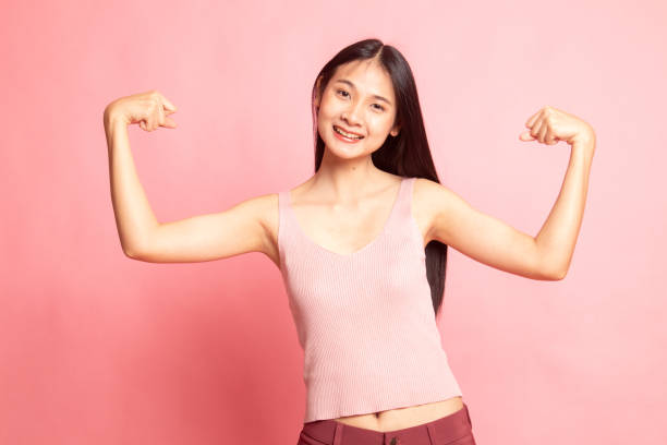 istock Beautiful young Asian woman flex bicep. 1129595288