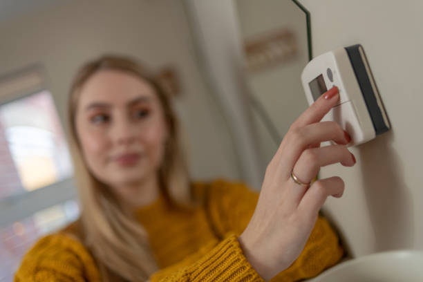 istock Woman changes the settings on a thermostat, central heating 1129599748