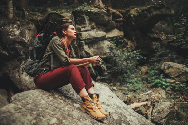 Pleased young woman sitting on the stone in the forest Thoughtful young woman spending an active weekend in the forest while sitting on the stone timberland arizona stock pictures, royalty-free photos & images