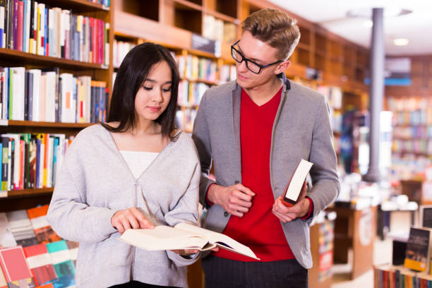 istock guy and girl  choosing and discussing books 1129605087