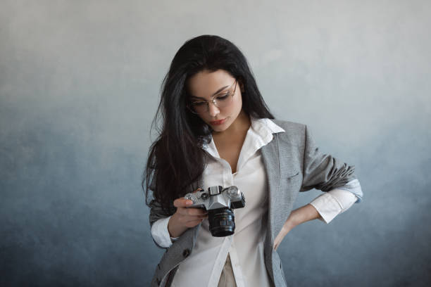 istock Beautiful young woman with camera 1129605140