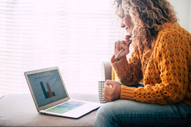 молодая женщина на дому работать с технологией интернет подключен ноутбук сесть на диван для альтернативных внештатных цифровых кочевник� - buying shopping computer cup стоковые фото и изображения