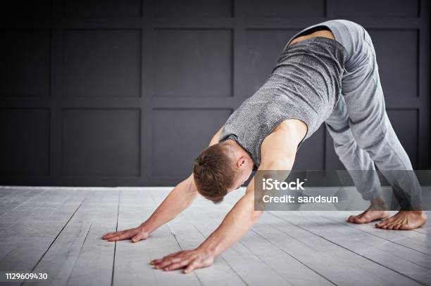 Young Strong Man Practices Yoga At The Yoga Studio Stock Photo - Download Image Now - Downward Facing Dog Position, Men, Only Men