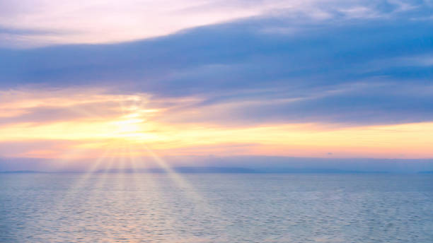 istock Dreamy Soft Sunrise over Smooth Sea with Sun and Sun Rays 1129611684
