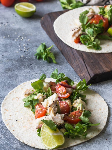 istock Tortillas with vegetables and white fish. Avocados, tomatoes, red onions and cod pieces sprinkled with sesame and lime juice in tortillas. Mexican food. 1129614823