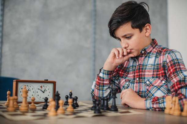 istock Smart boy playing chess in school of chess 1129615705