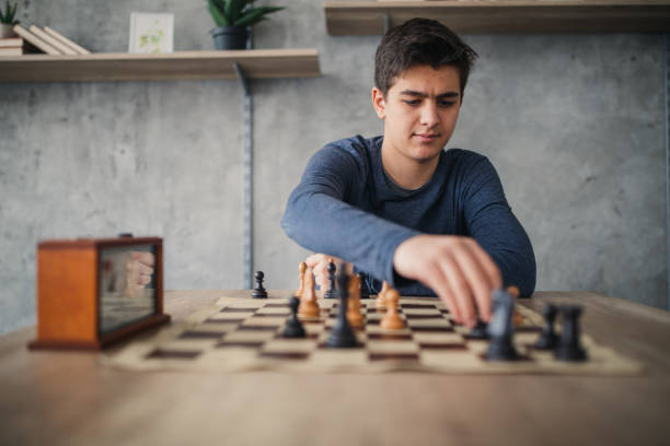 Teenage boy playing chess alone One teenage boy, playing chess in school of chess alone. chess timer stock pictures, royalty-free photos & images