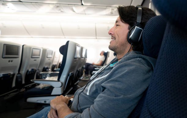 istock Male traveler watching in-flight entertainment using headphones 1129618428