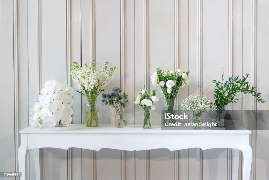 simply composition of different white flower in vase on white vintage table Flower Stock Photo