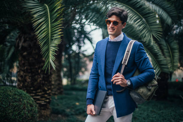 istock Smiling businessman with backpack and laptop 1129621721