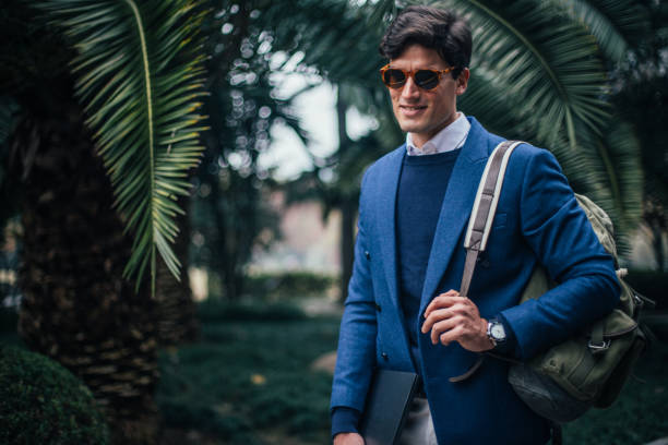 istock Man with backpack and laptop walking in the park 1129622861