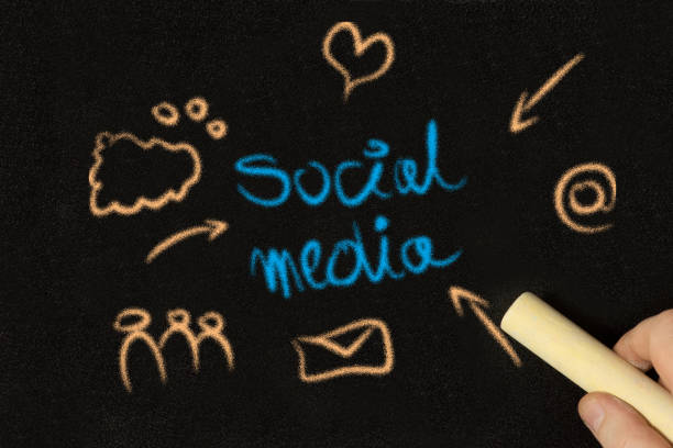 A man paints various symbols for social media on the chalkboard