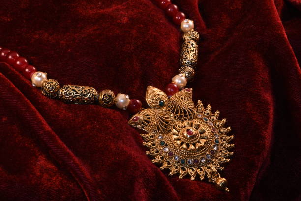 istock Designer beautiful golden necklace closeup macro image on red background. 1129629131