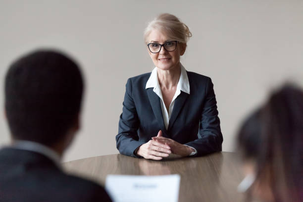 lächelnd im mittleren alter weiblicher job bewerber machen ersten eindruck im interview - leadership business women senior adult stock-fotos und bilder