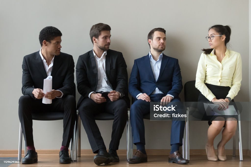 Diverse männliche Bewerber Blick auf weibliche Rivalen warten interview - Lizenzfrei Geschlechtsdiskriminierung Stock-Foto