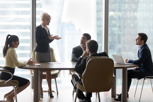 istock Mature female manager speaking to executive team at group meeting 1129629366