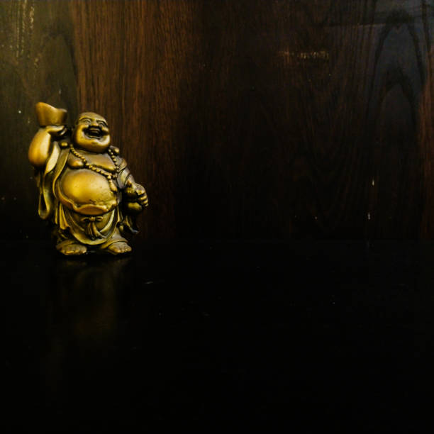 istock golden laughing buddha with wooden background 1129630007