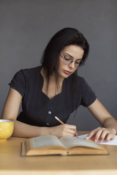 istock Beautiful young woman in glasses reading a book. 1129635951