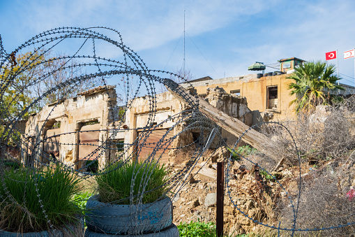 Nicosia, Cyprus - November 26, 2018: Barbed wire and a sentry post with flags in the background at the United Nations buffer zone (Green line) in divided Nicosia, capital of the island of Cyprus