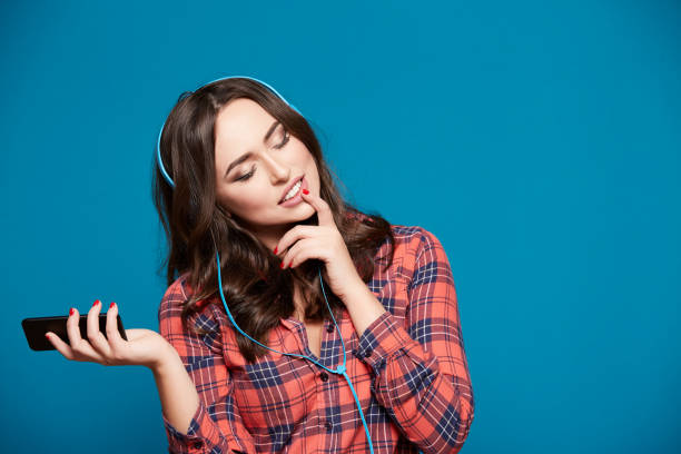 istock Pretty young girl posing at blue background 1129638381