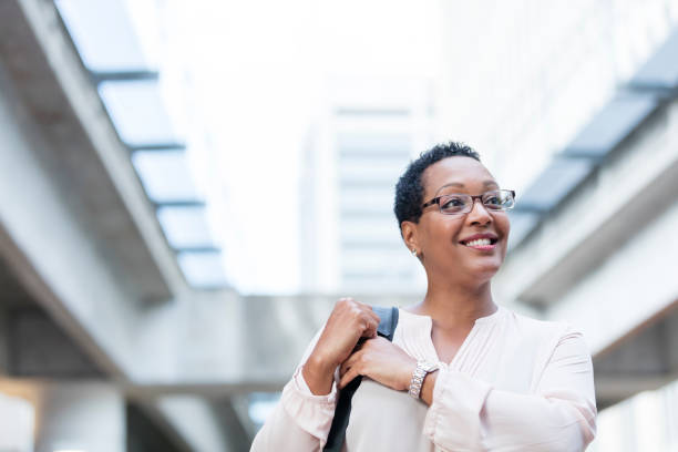 도시 거리에 걷는 중 년 아프리카계 미국인 여자 - business smiling walking outdoors 뉴스 사진 이미지