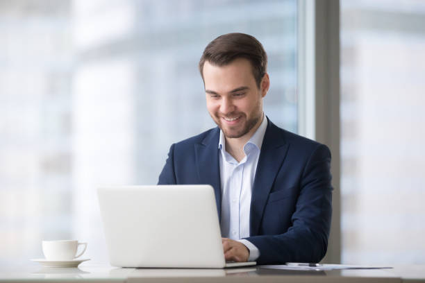 istock Happy businessman in suit using laptop software at workplace 1129638541