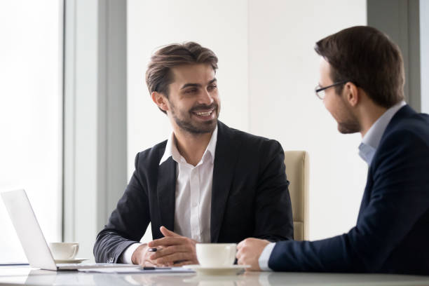 istock Happy businessmen partners executives talking at work enjoy teamwork 1129638547