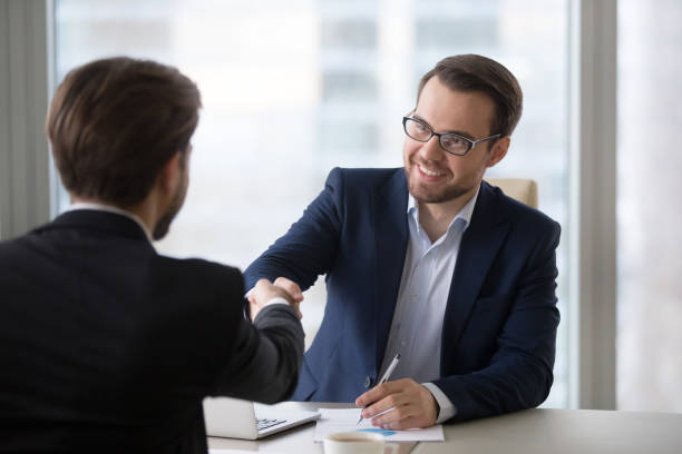 istock Smiling manager handshaking client applicant at meeting or job interview 1129638563