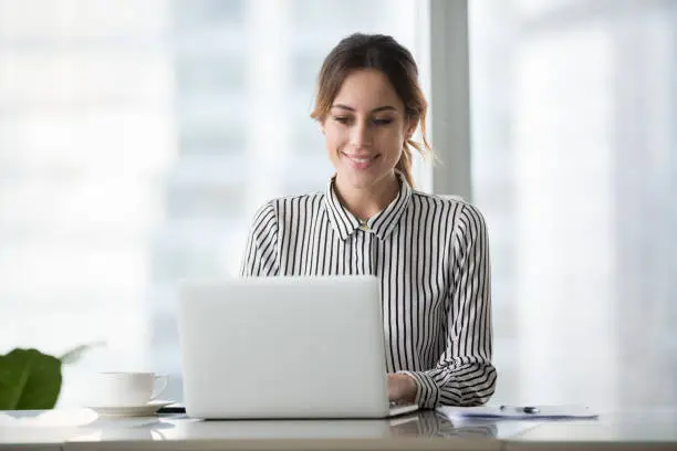 Photo of Happy businesswoman executive working online on laptop at office desk