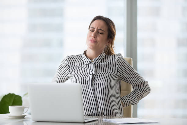 Tired fatigued businesswoman worker rubbing back feeling lower lumbar pain Tired fatigued businesswoman worker rubbing back feeling pain in kidneys suffers from lower lumbar backache after sedentary computer work sitting in incorrect posture on uncomfortable office chair office back pain stock pictures, royalty-free photos & images