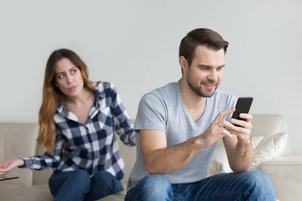 Jealous suspicious wife arguing with obsessed husband holding phone Jealous suspicious mad wife arguing with obsessed husband holding phone texting cheating on cellphone, distrustful girlfriend annoyed with boyfriend mobile addiction, distrust social media dependence indifference stock pictures, royalty-free photos & images
