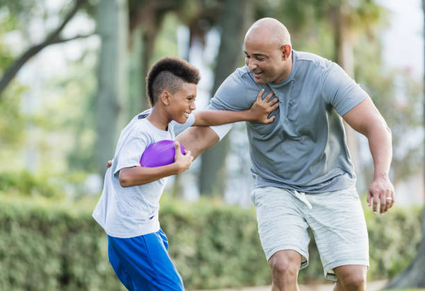 istock Father and son playing football in park 1129641721