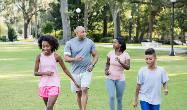 istock Interracial family with two children walking in park 1129643304